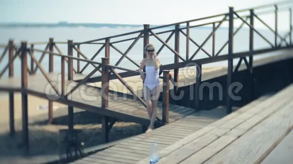 热辣的女孩站在沙滩上的桥上晒太阳4k视频的预览图
