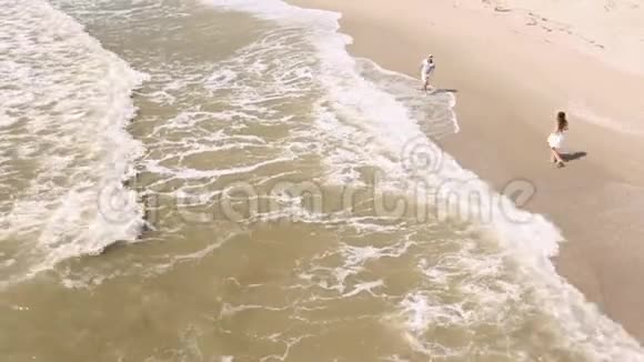 在海滩上跑步的夫妇那个男人正在向那个女人泼水从侧面看视频的预览图