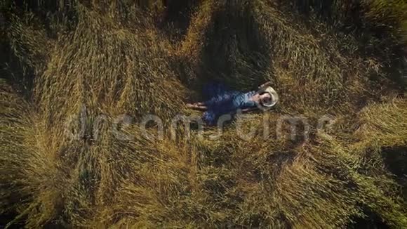 空中飞行穿着乡村服装的漂亮女孩躺在干草堆里戴帽子的年轻女人与自然统一的概念视频的预览图