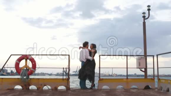 浪漫的构图拥抱和亲吻夫妇在多风的天气码头视频的预览图