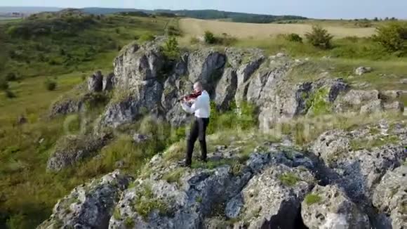 小提琴手在岩石高原上拉小提琴视频的预览图