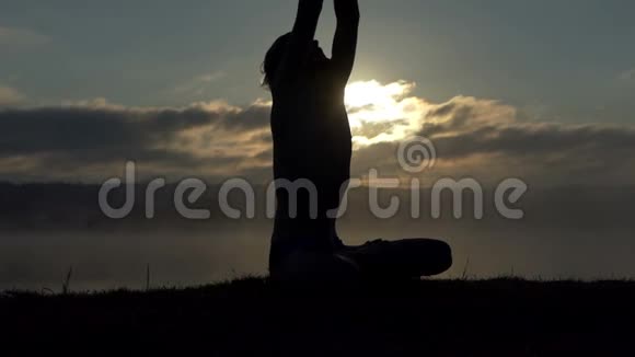 灵性的人坐在湖岸上在日落时缓慢地练习瑜伽视频的预览图