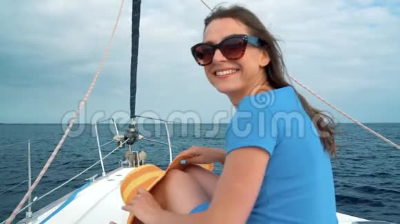 戴着黄色帽子的女人和穿着蓝色衣服的女孩在海洋的夏季靠近灯塔的游艇上休息慢慢视频的预览图