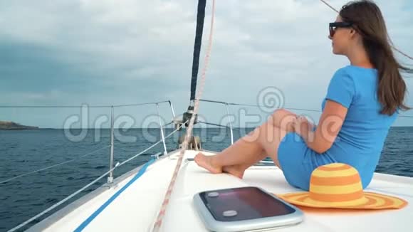 戴着黄色帽子的女人和穿着蓝色衣服的女孩在海洋的夏季靠近灯塔的游艇上休息慢慢视频的预览图