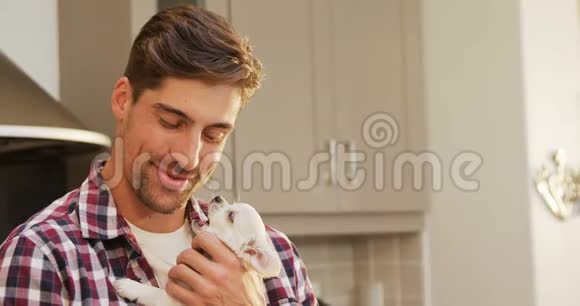 微笑的年轻人在厨房里抱着宠物视频的预览图