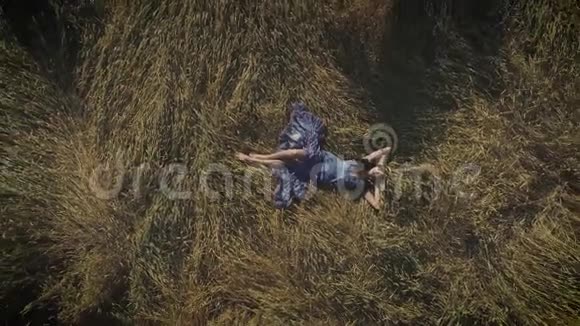 空中飞行穿着乡村服装的漂亮女孩躺在干草堆里戴帽子的年轻女人与自然统一的概念视频的预览图