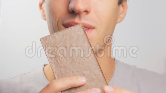 年轻人吃白色背景的巧克力棒视频的预览图