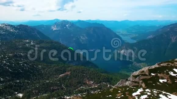 一架绿色降落伞飞行滑翔伞从奥地利雪山全景视频的预览图
