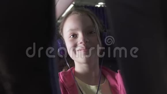 快乐的少女在飞机舱内听耳机上的音乐在旅行时听股票录像视频的预览图