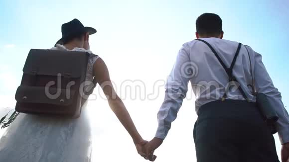 这对幸福的新婚夫妇手牵着手头对头站在天空的背景下这就是视频的预览图