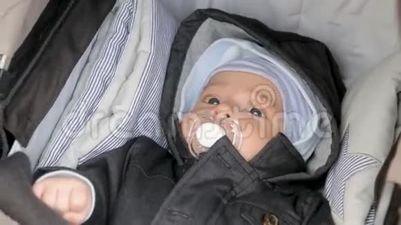 妈妈从一个躺在婴儿车里的孩子嘴里拿出一个奶嘴视频的预览图