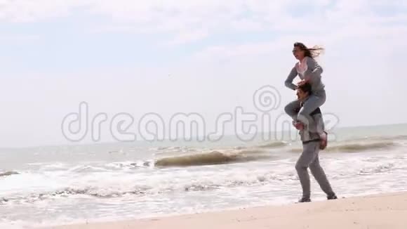 那个男人把那个女人扛在肩上在海滩上奔跑视频的预览图