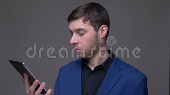 年轻英俊的白种人的特写镜头使用平板电脑并显示绿色彩色屏幕与背景相机视频的预览图