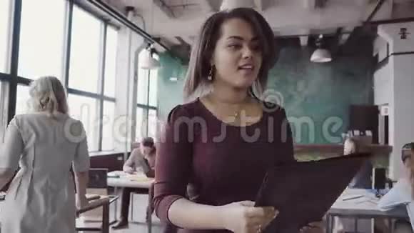 非洲女人来上班有魅力的女性与同事打招呼阅读文件在办公室的混合种族小组视频的预览图