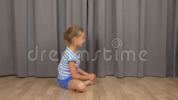 年轻女孩做瑜伽蝴蝶姿势白姑娘在室内客厅伸懒腰视频的预览图