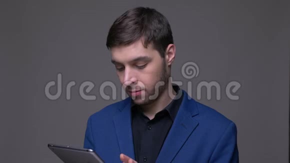 年轻英俊的白种人用平板电脑拍摄特写镜头并用背景镜头显示绿色屏幕视频的预览图