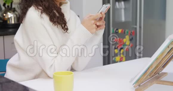 幸福的女人靠在厨房柜台上用她的手机4K4K视频的预览图