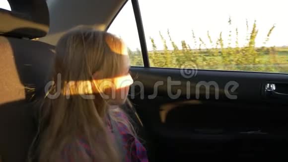 年轻的白人女孩看着窗户开车日落夏秋的傍晚金色的日落视频的预览图