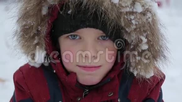 美丽的孩子在冬天的公园里微笑下雪了视频的预览图