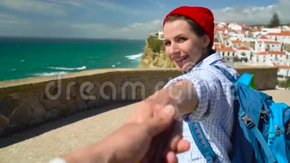 跟我来一个快乐的年轻女人她戴着红帽子背着背包拉着一个男人他的手在玛尔的阿岑哈视频的预览图