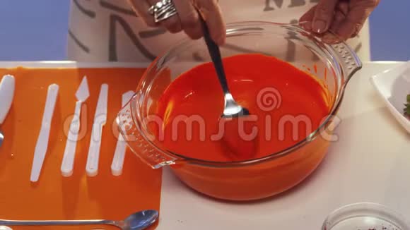 橙色物质从勺子滴到宽边的大玻璃锅里视频的预览图