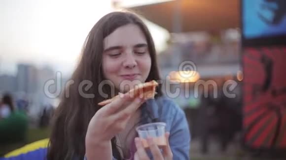 年轻漂亮的黑发女孩有雀斑夏天在公园吃披萨笑笑视频的预览图