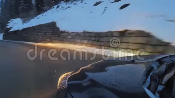 冬季白天在山路上行驶带有前灯的黑色汽车视频的预览图