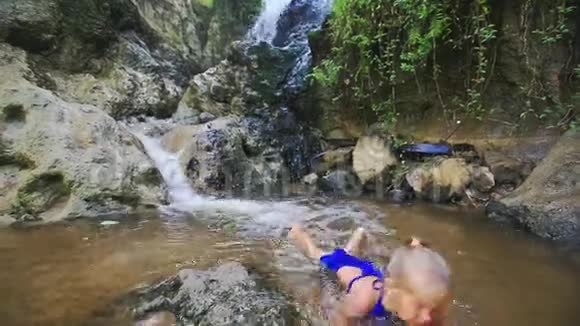 特写女郎通过瀑布在浅水区游泳视频的预览图