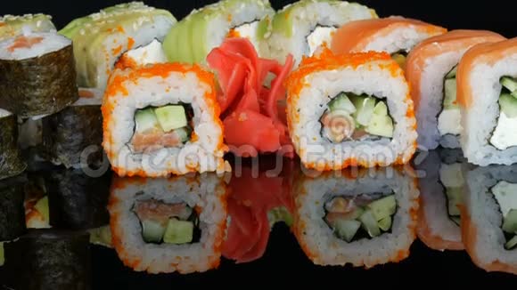 各种彩色寿司卷集和生姜在镜面上的黑色背景日本料理工作室视频的预览图