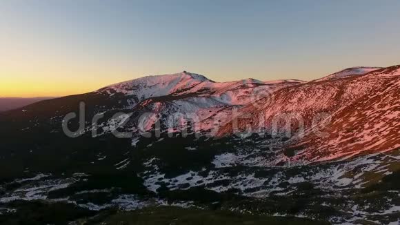 在日落或日出时在冬季雪山和森林的背面俯视黄昏或黎明视频的预览图