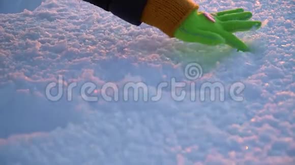 女孩手在雪中描绘心灵戴绿色手套的手特写镜头视频的预览图