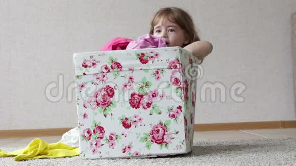 小女孩坐在一个彩色盒子里她玩衣服视频的预览图