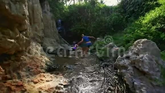 小女孩牵着妈妈手在小溪的石头上跳视频的预览图