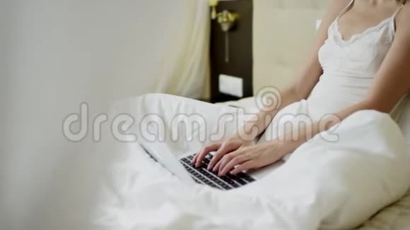 快乐的女人早上在床上用她的笔记本电脑工作视频的预览图
