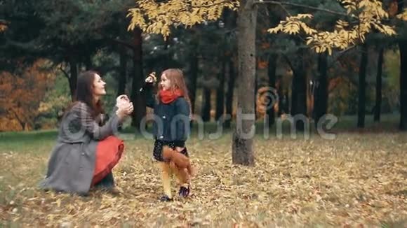 可爱有趣的小女孩给她的母亲收集了一束野花在惊人的秋天公园慢动作视频的预览图