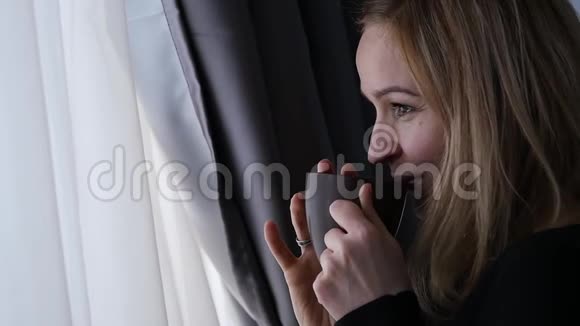 漂亮的女人喝咖啡或茶看着窗外慢动作视频的预览图