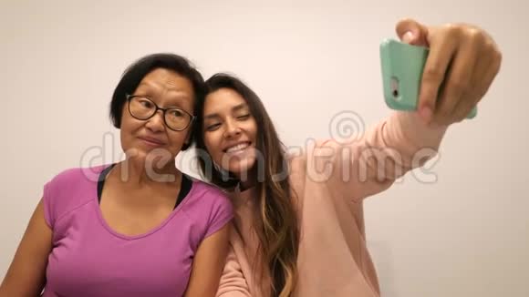 高中妈妈和小女儿用手机拍自拍4K视频的预览图
