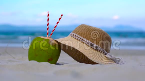 一个美丽的白色沙滩的摘要年轻的椰子两个饮水管和一个女人的帽子前面的海洋视频的预览图