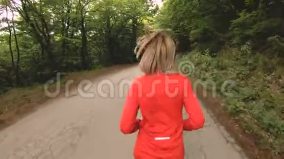 奔跑的女孩在夏季森林里做户外运动的金发女孩后视慢动作广角特写视频的预览图