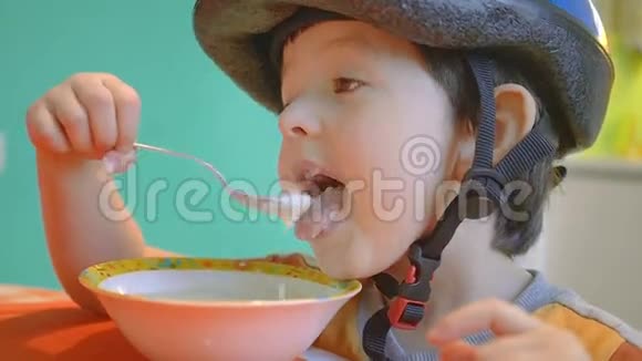 可爱的4岁男孩戴着运动头盔早上吃粥视频的预览图