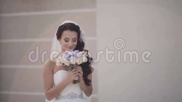 美丽的黑发新娘手持花束穿婚纱的女人闻到了花的味道婚礼前的女性视频的预览图