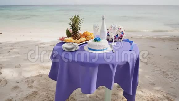 一张装饰的婚礼桌在沙滩上放着水果蛋糕香槟和酒杯热带菲律宾视频的预览图