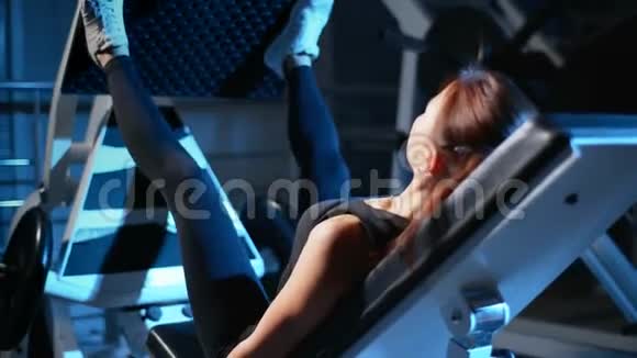 那个女孩正在健身房训练腿按在模拟器中用于大腿和臀部的背部视频的预览图