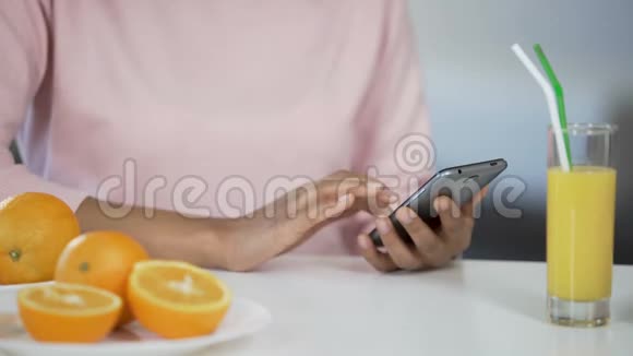 多种族女孩在厨房里使用智能手机桌上放橘子医疗保健视频的预览图