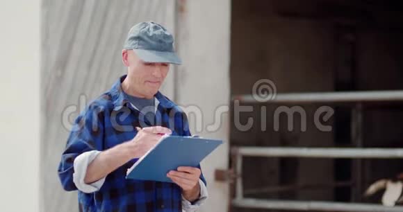 农夫一边打手势一边在剪贴板上对着谷仓写字视频的预览图