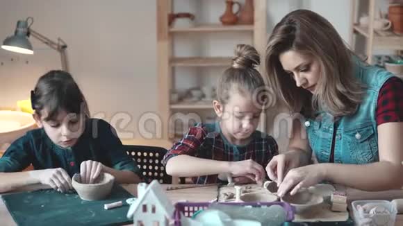 一位有两个小女儿的年轻母亲在一个家庭作坊里从事创造力孩子们用粘土做工艺品视频的预览图