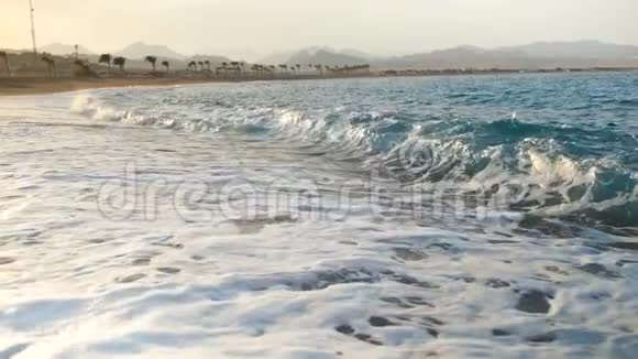 金色沙滩上美丽的日落在海浪上缓慢移动的画面视频的预览图