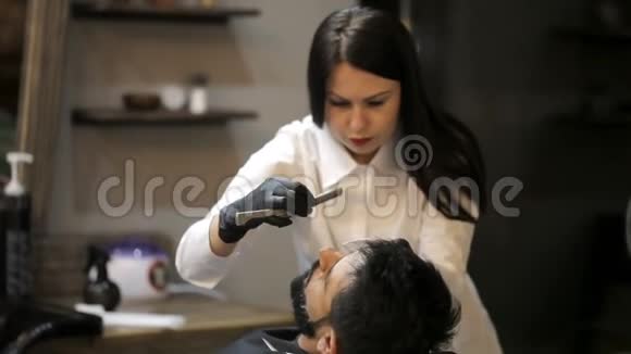 理发师女孩用直剃须刀做理发胡须客户视频的预览图