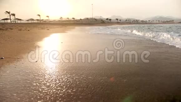 金色沙滩上美丽的日落在海浪上缓慢移动的画面视频的预览图