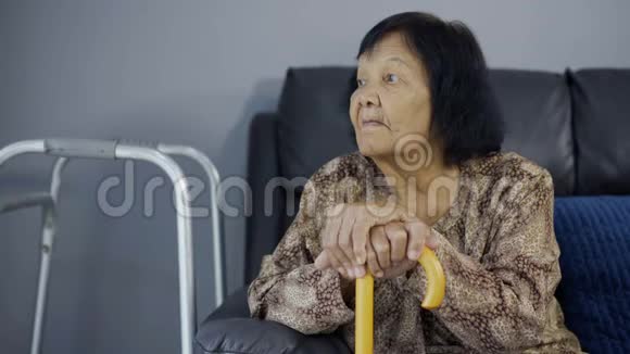 一位手持拐杖的老妇人坐在沙发上视频的预览图